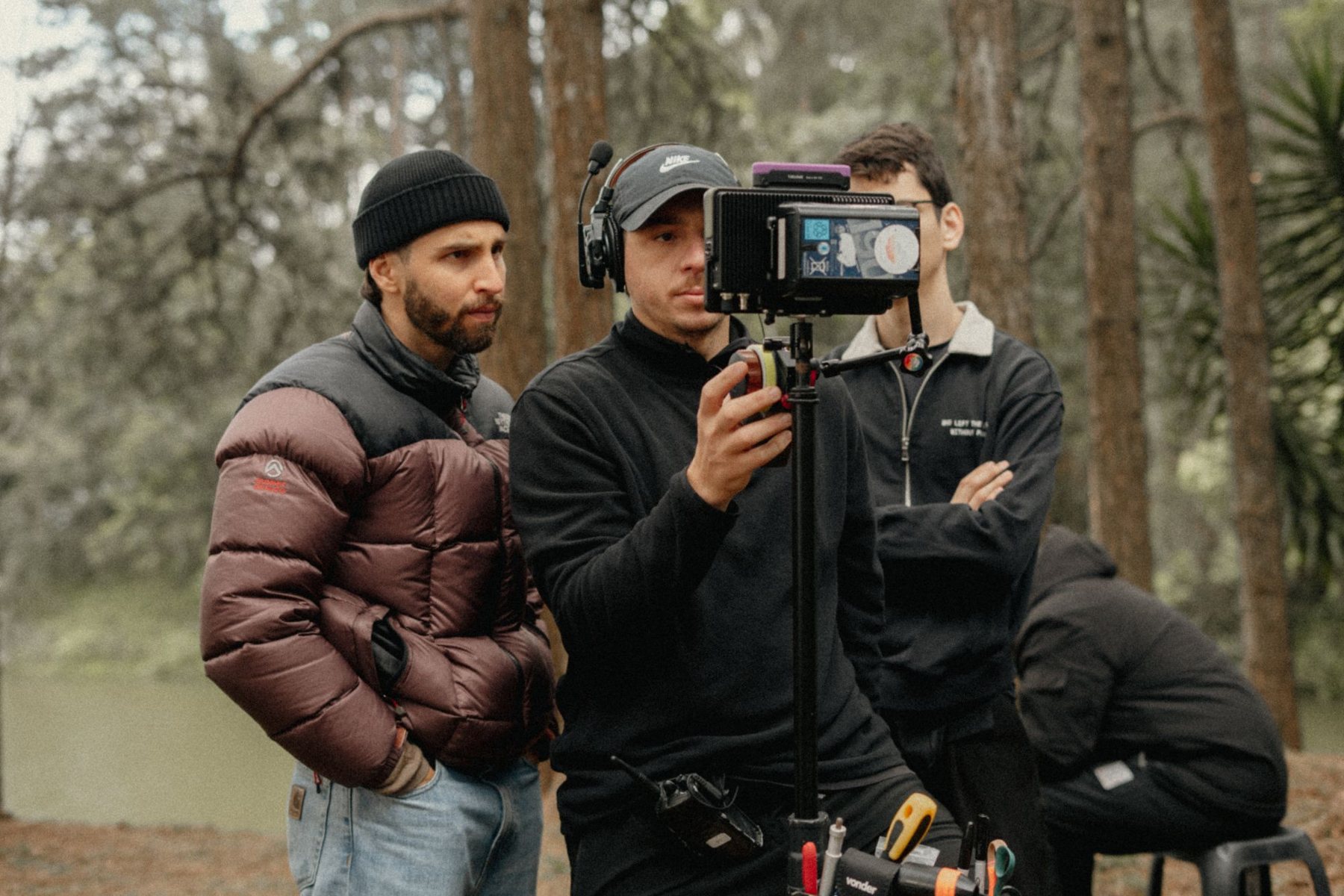 Ricardo on set in a forest, watching the monitor with the camera team